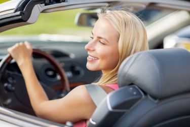 happy young woman driving convertible car